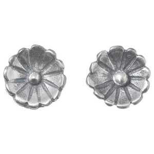 May include: Two silver-colored flower-shaped stud earrings. Each earring has a central, raised, circular element surrounded by petals. The earrings are made of a metallic material and are set against a white background.