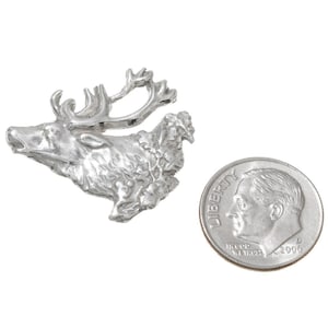 May include: A silver-toned elk head pin with a detailed design. The pin is about the size of a dime.