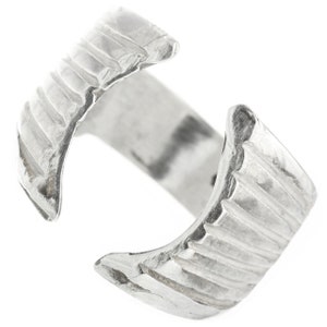 May include: A silver ring with a textured, ridged design. The ring is open on one side, making it adjustable.