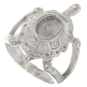 May include: A silver turtle ring with a detailed shell design. The ring is open on the side and has a smooth band.