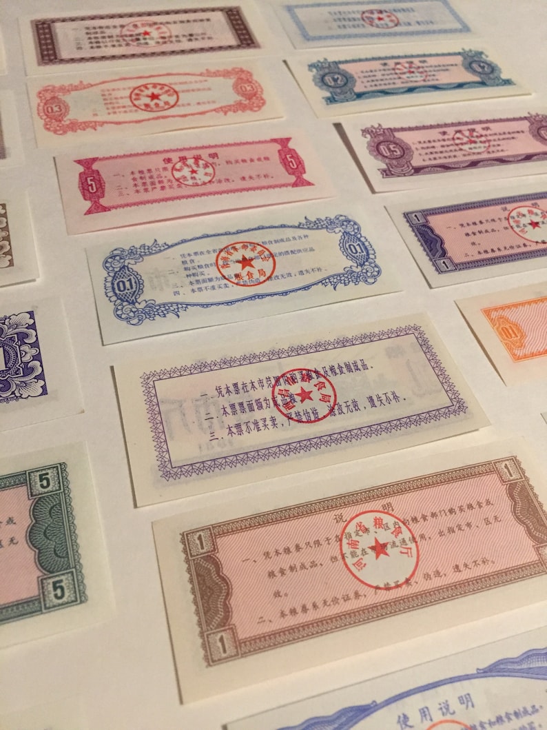 May include: A collection of vintage Chinese ration coupons with red star seals. The coupons are printed in various colors, including pink, blue, and green. The text on the coupons is in Chinese.