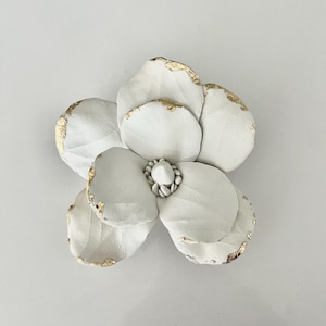 Arte mural de arcilla con forma de magnolia y detalles en lámina dorada.