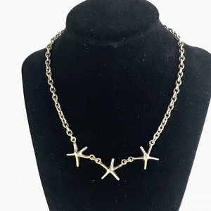 May include: Silver necklace with a chain and three star-shaped pendants.
