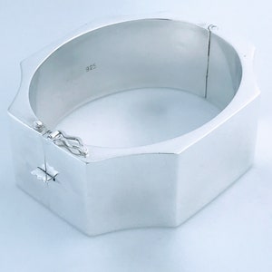 May include: A silver hinged bangle bracelet with a octagonal shape and a 925 hallmark.