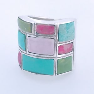 May include: A silver ring with a geometric design featuring turquoise, pink, and green stones.