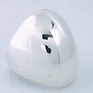 May include: A smooth, white, triangular-shaped stone with a polished surface. The object features a distinct, natural fissure or crack running across the top section, revealing a darker, greyish interior texture within the white stone structure.