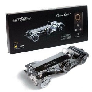 May include: A silver metal model car kit of a classic convertible sports car. The box shows the car assembled and includes the text "Time for Machine" and "Glorious Cabrio 2".