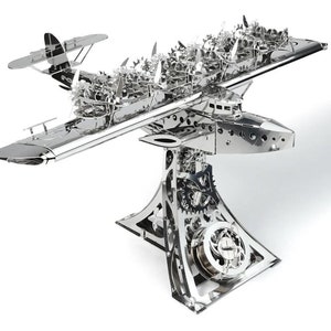 May include: A silver metal model of a seaplane with intricate details and gears. The seaplane is mounted on a stand with gears and is ready to take flight.