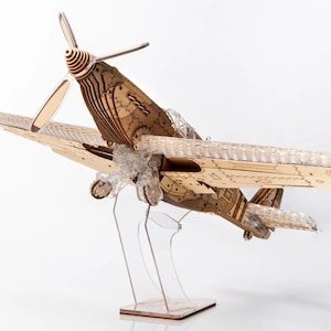 May include: A wooden model aeroplane with a brown finish and a propeller. The aeroplane is on a clear acrylic stand.