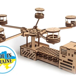 May include: A wooden model of a Ferris wheel with four passenger cars. The model is made of natural wood and has a detailed design. The model is made in Ukraine, as indicated by the label on the base.