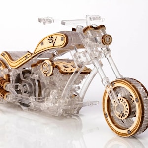 May include: A detailed wooden model of a motorcycle with a clear acrylic frame. The model has a detailed engine and wheels.