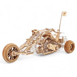 May include: A detailed wooden model of a three-wheeled motorcycle. The model has a clear plastic body and wooden wheels, engine, and frame. A small flag is attached to the back. The motorcycle model is a DIY project, ideal for hobbyists.