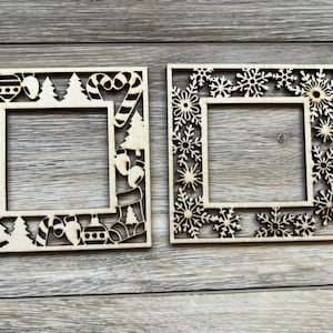 May include: Two wooden square frames with intricate cut-out designs. One frame features Christmas-themed elements like candy canes, trees, and ornaments. The other frame is decorated with snowflakes, perfect for holiday crafts.
