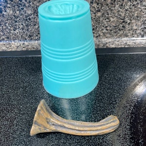 May include: A light blue plastic cup with a textured surface and a curved, gold-colored metal handle.