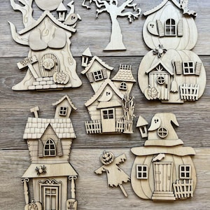 May include: A collection of unfinished wooden Halloween-themed cutouts. The set includes various house shapes, a tree, a scarecrow, and a moon. Some houses are shaped like pumpkins. One cutout has the text "DO NOT ENTER".