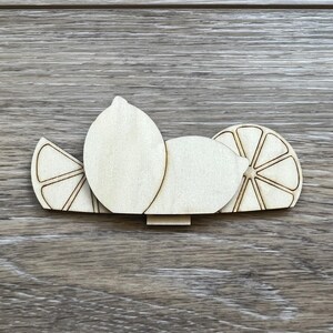 May include: Three wooden lemon slices, two whole lemons and one lemon wedge, all cut out in a simple design.
