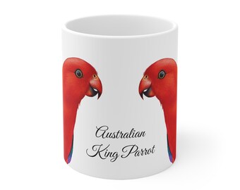 Puede incluir: Taza de cerámica blanca con dos ilustraciones de un loro rey australiano. Los loros son rojos con picos negros y detalles azules y verdes. Las palabras "Australian King Parrot" están escritas en negro.