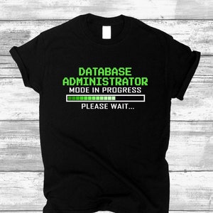 Könnte beinhalten: Schwarzes T-Shirt mit grünem Text, der "Database Administrator Mode in Progress" lautet, mit einer grünen Fortschrittsanzeige und dem Text "Bitte warten..."