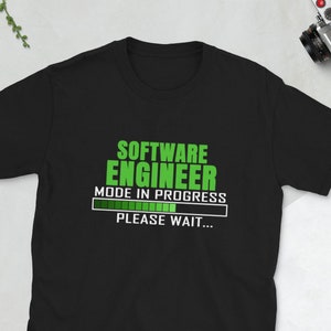 Può includere: Maglietta nera con una grafica verde che dice "Software Engineer Mode in Progress" con una barra di avanzamento e il testo "Please Wait..."