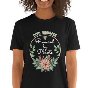 Puede incluir: Camiseta negra con un gráfico circular blanco que dice "Civil Engineer Powered by Plants" con un diseño floral alrededor del círculo.