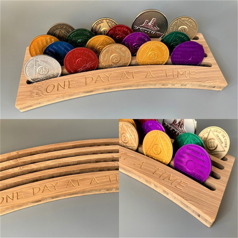 May include: A wooden display stand with a curved shape and the words "One Day At A Time" engraved on the front. The stand holds a collection of round, colorful tokens with different designs.