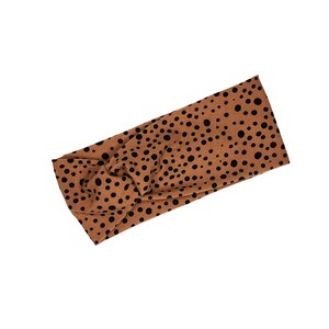 May include: A brown headband with a black polka dot pattern. The headband is made of a soft, stretchy fabric and is designed to be worn around the head.