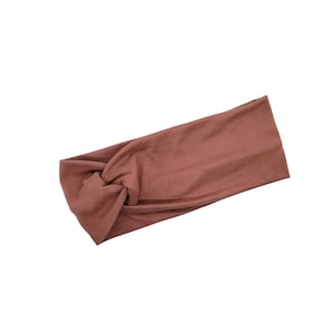 May include: A brown knotted headband made of soft fabric.