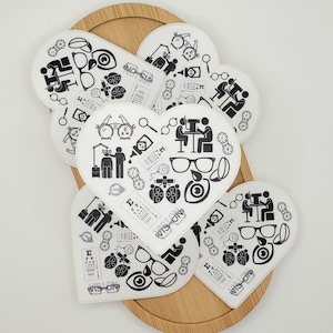 May include: A set of six heart-shaped stickers with black and white illustrations of eye care related icons, including an eye chart, glasses, and an eye exam. The stickers have the text "VISION" printed on them.