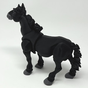 May include: A black horse figurine with a detailed mane and tail. The horse is posed in a standing position, with its head turned slightly to the left. The hooves are gray. The figurine is made of a matte material.