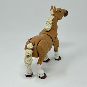 May include: A brown toy horse with a cream-colored mane and tail. The horse has white markings on its legs and hooves. The toy is posed with its head turned to the side, and its tail is curled.