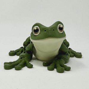 May include: A green frog figurine with large, expressive eyes and a white belly. The frog is in a seated position with its legs extended. The figurine has a smooth, glossy finish and is set against a white background.