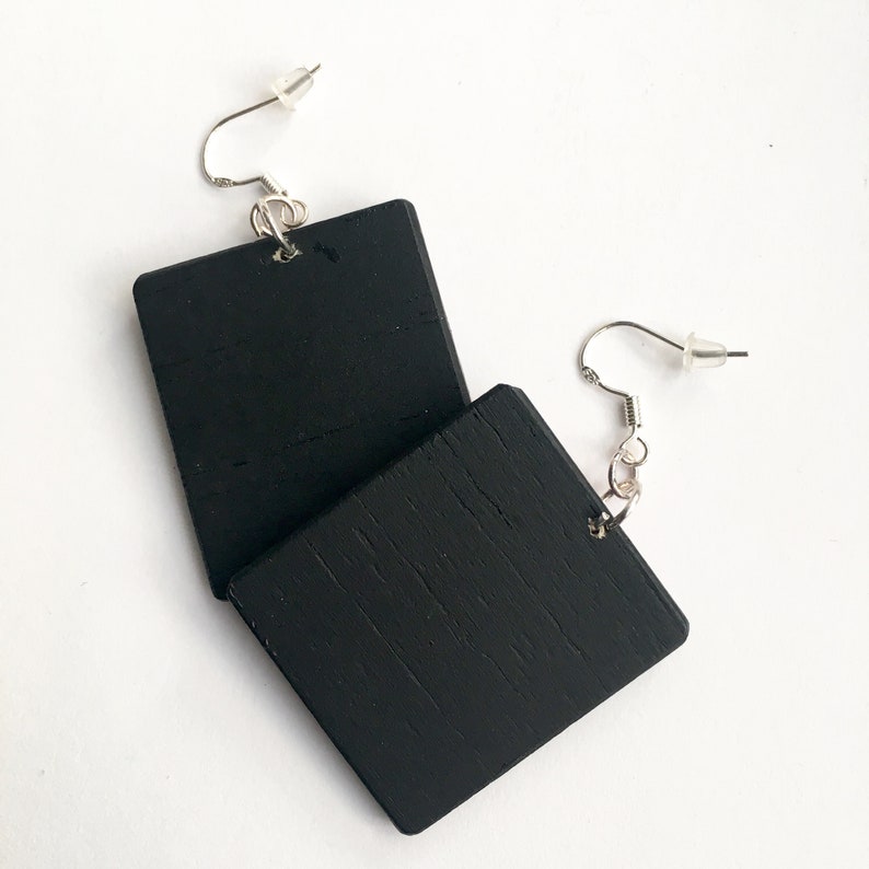 May include: A pair of black square wooden earrings with silver hooks.