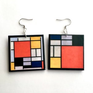 May include: A pair of square earrings with a geometric design featuring red, yellow, blue, black and white squares. The earrings are made of wood and have silver hooks.