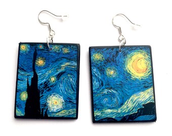 May include: A pair of square wooden earrings with a print of Vincent van Gogh's "Starry Night" painting. The earrings have silver hooks.