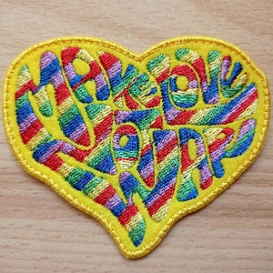May include: A yellow heart-shaped patch with rainbow stripes and the text "Make Love Not War" embroidered in colourful thread.