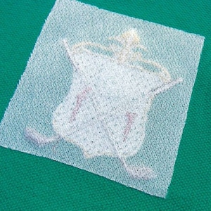 Op de afbeelding: Een witte stoffen patch met een bedrukt ontwerp van een golfer die een golfclub zwaait. De patch is op een groene achtergrond.