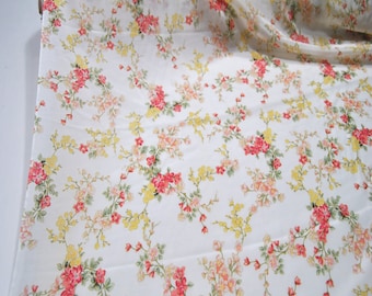 May include: White fabric with a floral print featuring small pink, yellow, and red flowers on a white background.