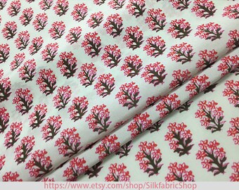 May include: White cotton fabric with a repeating pattern of pink and brown floral designs. The fabric is folded in half and the pattern is visible on both sides.