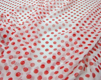May include: White sheer fabric with red polka dots. The fabric is folded and draped.