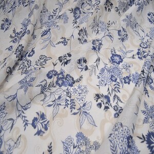 May include: White fabric with a blue floral pattern. The fabric has a sheer, almost translucent quality.