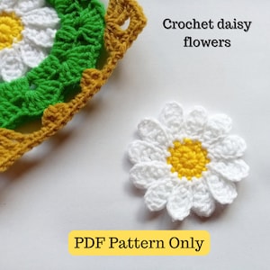 Può includere: Schema a uncinetto per un fiore di margherita. L'immagine mostra un fiore di margherita bianco all'uncinetto con un centro giallo. Il testo "Crochet daisy flowers" e "PDF Pattern Only" è anche visibile nell'immagine.