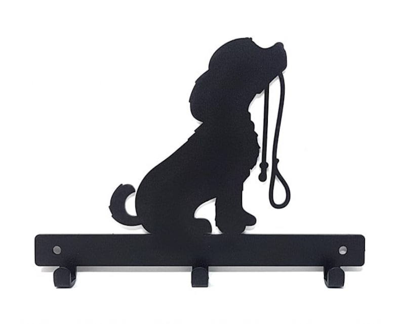 K&ouml;nnte beinhalten: Schwarzer Schl&uuml;sselhalter aus Metall in Form einer Hundesilhouette, die eine Leine h&auml;lt. Der Halter hat drei Haken zum Aufh&auml;ngen von Schl&uuml;sseln.