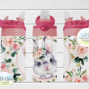 May include: A white 12oz flip-top water bottle with a sublimation design. The bottle features a watercolor illustration of a gray bunny wearing a floral crown, surrounded by pink roses and greenery. The lid and spout are pink.