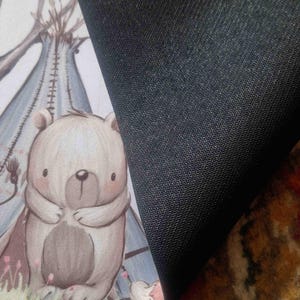 May include: A brown and white bear with a light blue teepee in the background. The bear is standing on a green patch of grass. The background is a light beige color.