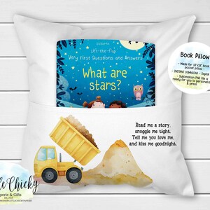 Könnte beinhalten: Ein weißes Buchkissen mit einer Tasche für ein kleines Buch. Das Buch trägt den Titel "What are stars?" und ist Teil der Usborne Lift-the-flap Very First Questions and Answers Reihe. Das Kissen zeigt einen gelben Kipplaster und einen Sandhaufen auf der Vorderseite. Der Text "Read me a story, snuggle me tight. Tell me you love me. And kiss me goodnight." ist auf dem Kissen aufgedruckt.