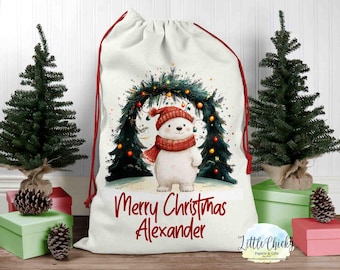 May include: A white Christmas stocking with a red drawstring and a cute illustration of a polar bear wearing a red scarf in front of a Christmas tree with lights. The stocking has the text "Merry Christmas Alexander" printed on it.