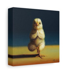 May include: A yellow baby chick stands on one leg in a yoga pose with its wings folded in front of its chest. The chick is against a blue background and a yellow surface.
