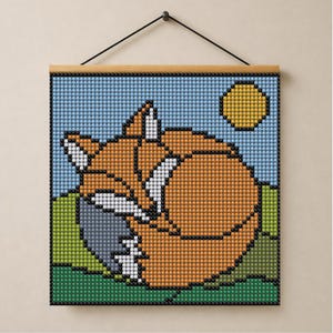 Könnte beinhalten: Ein quadratisches Diamond-Painting-Wandbild mit einem pixeligen orangefarbenen Fuchs, der sich auf einer grünen Wiese unter einem hellblauen Himmel mit einer gelben Sonne zusammenrollt. Das Bild ist auf einem Holzrahmen mit schwarzer Schnur.