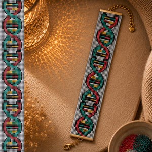 May include: A rectangular beaded bracelet featuring a repeating DNA double helix pattern in shades of teal, red, and yellow against a light gray background. The bracelet has gold-toned metal end bars and a gold-toned chain with a heart charm.