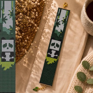 May include: A rectangular beaded bracelet featuring a pixelated panda design in shades of black, white, and green. The bracelet has a dark green background, a gold-toned lobster clasp at the top, and a small gold-toned leaf charm at the bottom.